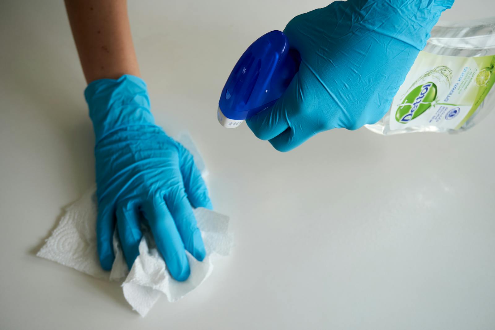 Blue-gloved hands disinfecting a customer-facing surface