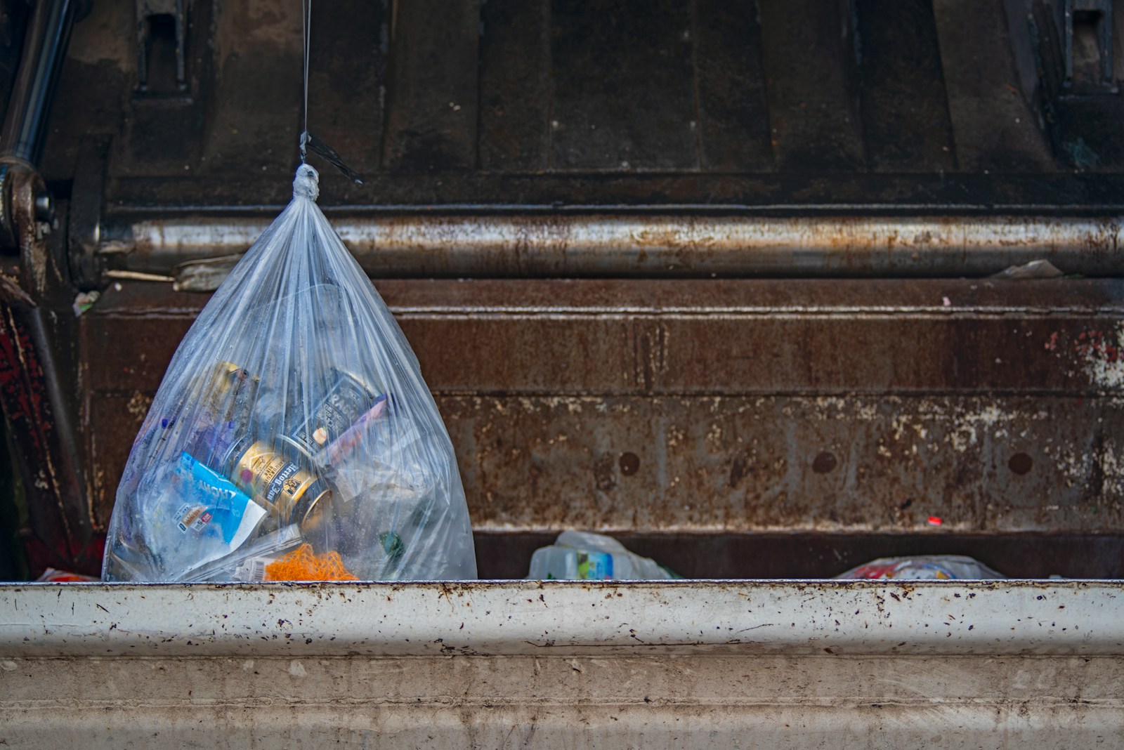 Waste bags placed in a large dumpster during a clearance